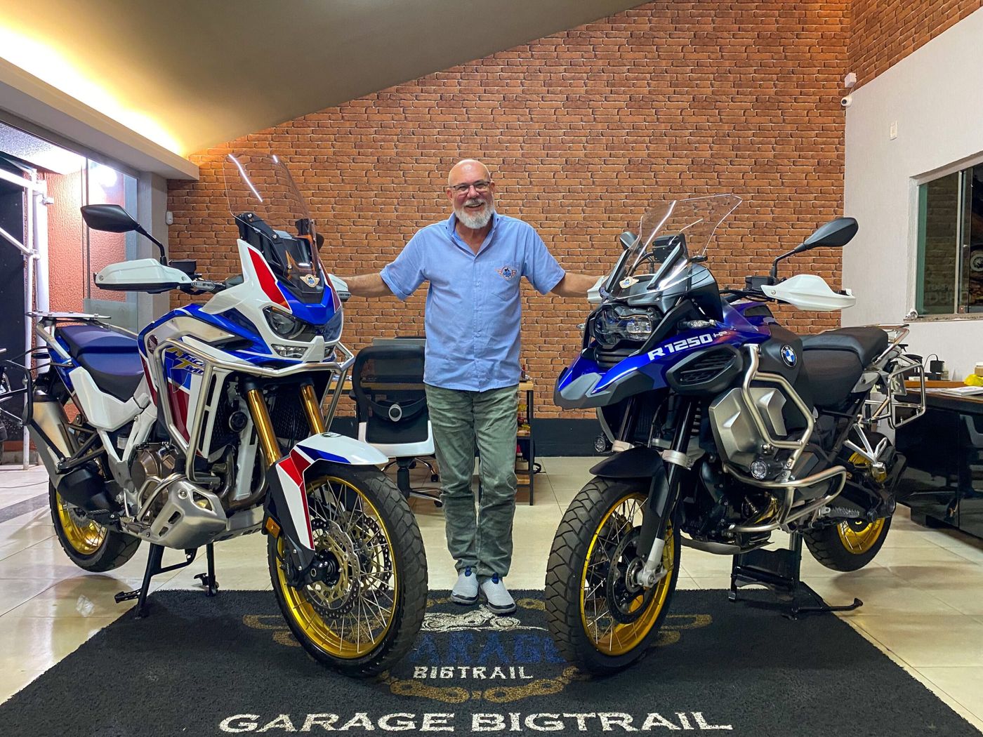 Celso com uma Africa Twin e uma BMW R 1250 GS na loja da Garage BigTrail